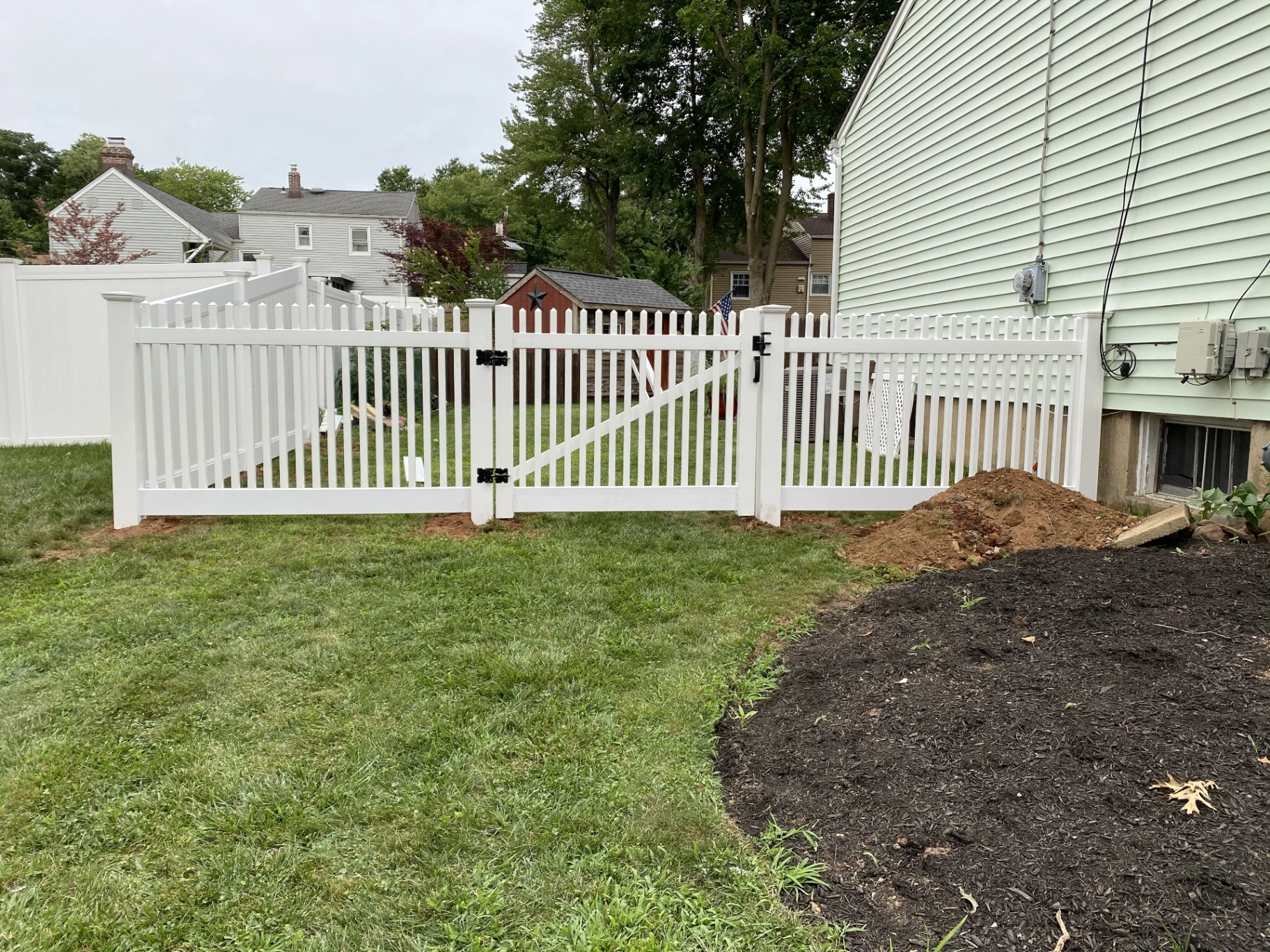 White vinyl spaced picket fence with double gate in a residential backyard in New Jersey installed by Fred's Fence