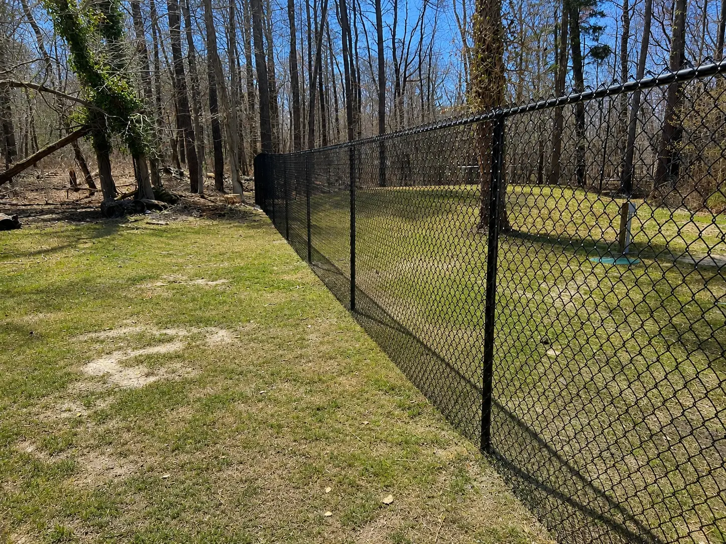 Black chain link fence installation along a wooded residential property in New Jersey by Fred's Fence