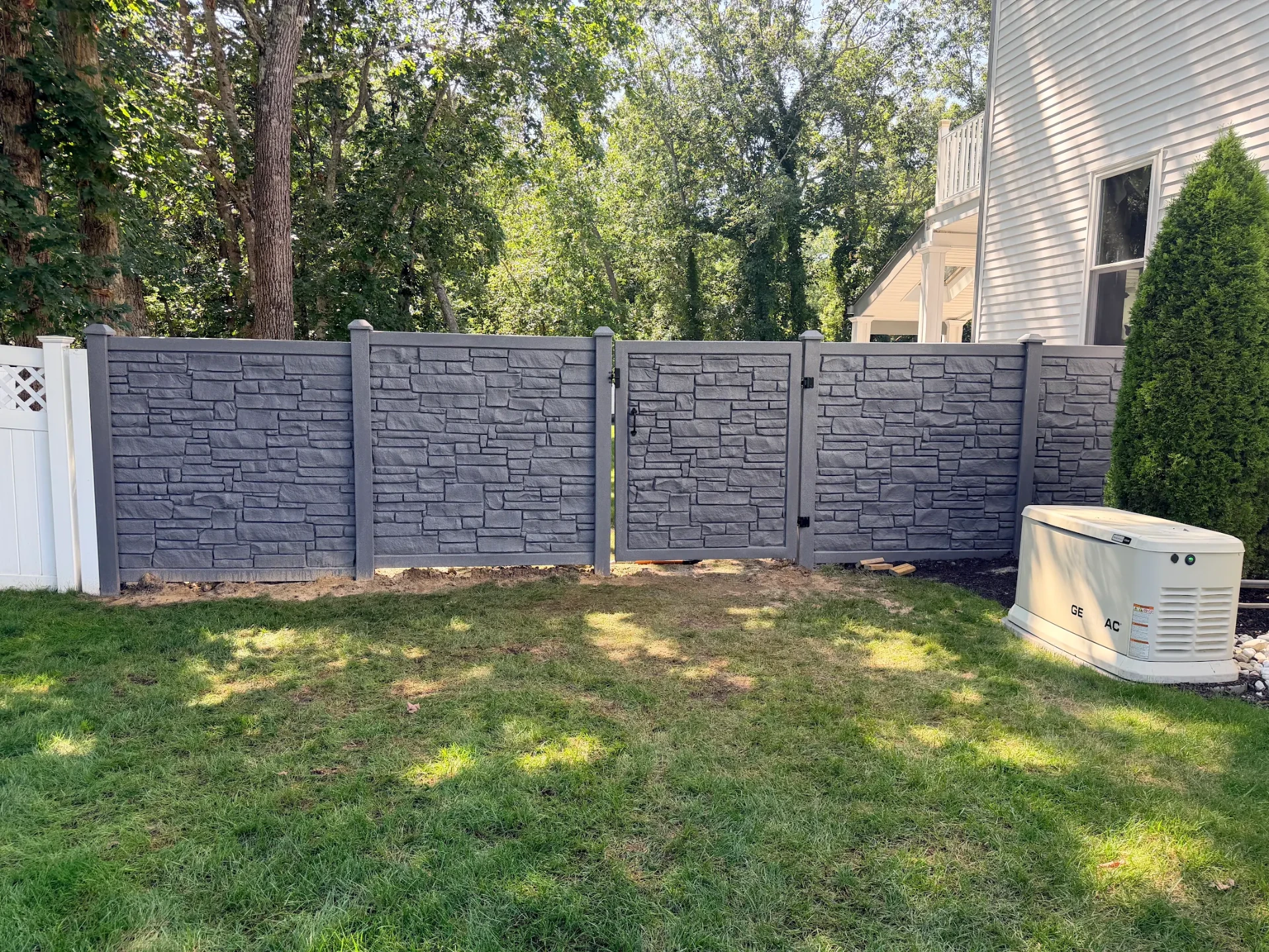 Stone-look vinyl privacy fence with gate installed by Fred's Fence