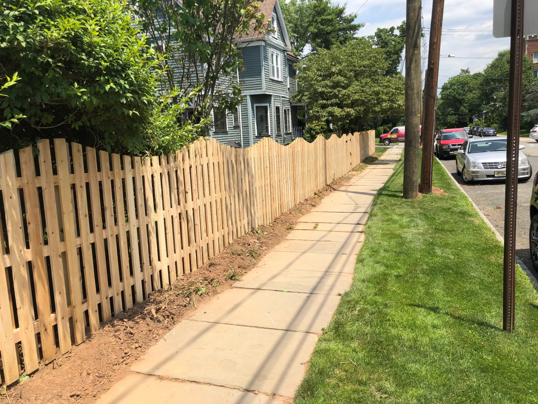 Cedar shadow box fence with scalloped top along a residential sidewalk in New Jersey by Fred's Fence