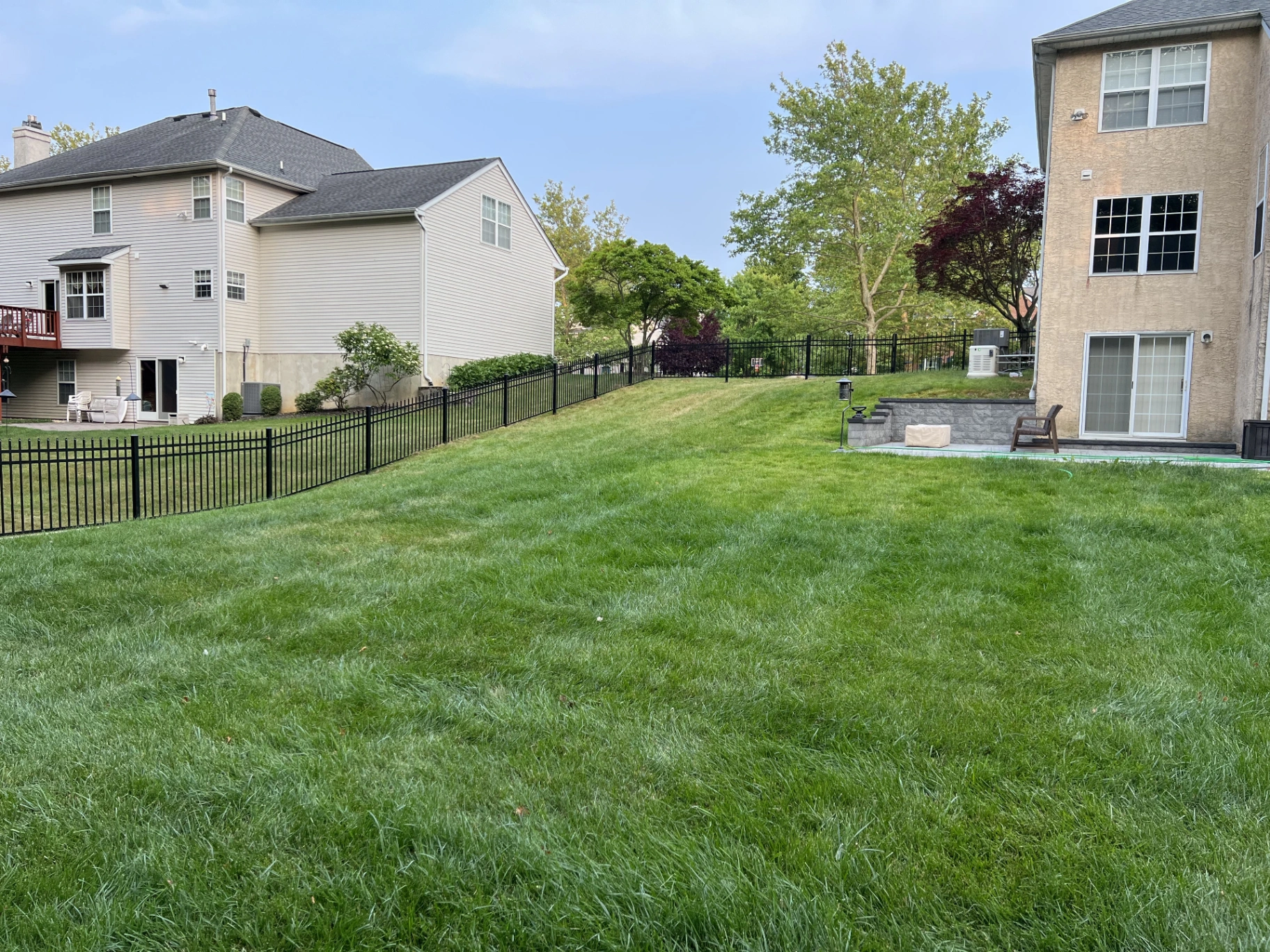 Black aluminum fence along a residential property line between two homes in New Jersey by Fred's Fence