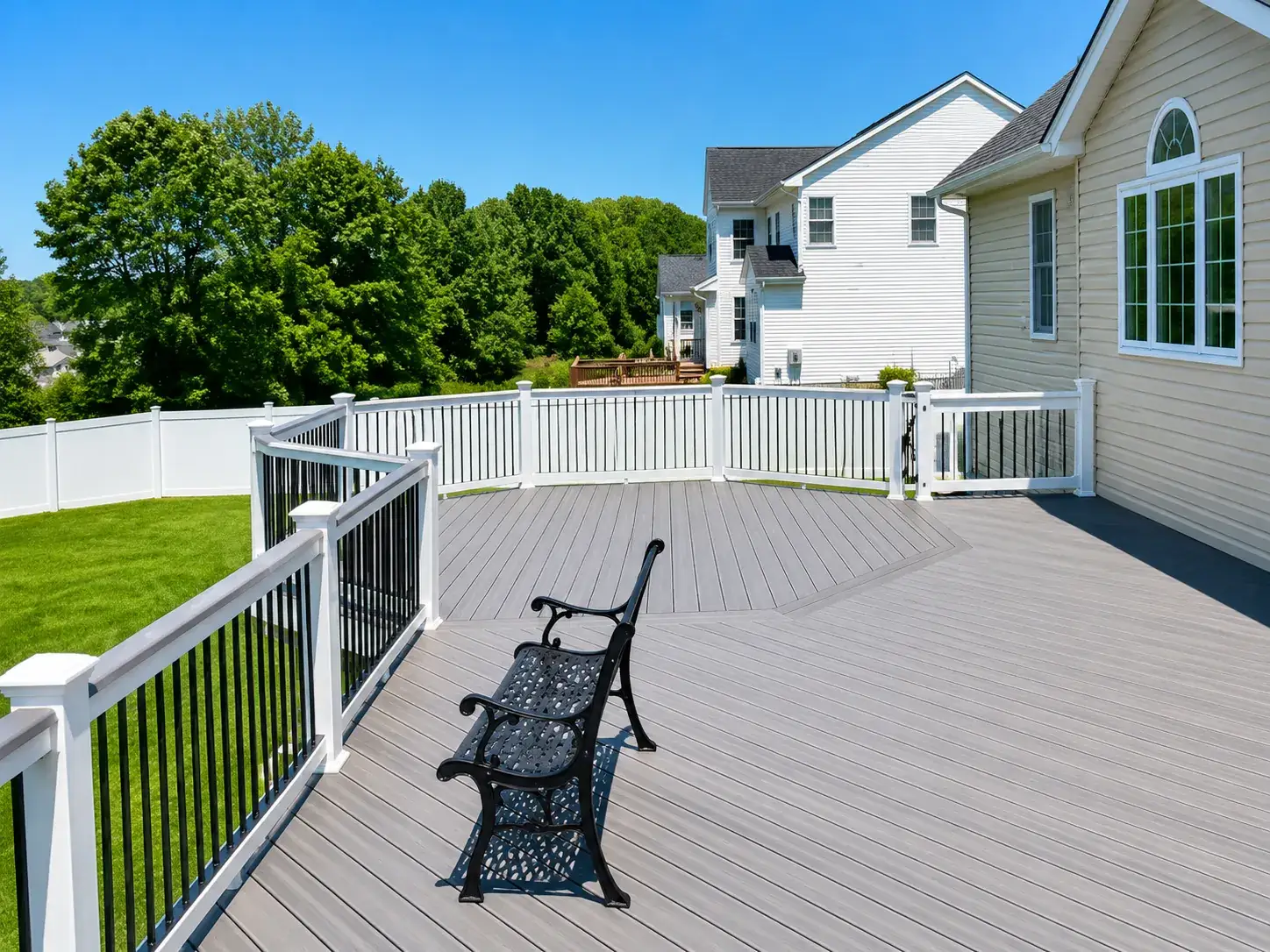 Composite deck with white vinyl railing and black aluminum balusters installed by Fred's Fence