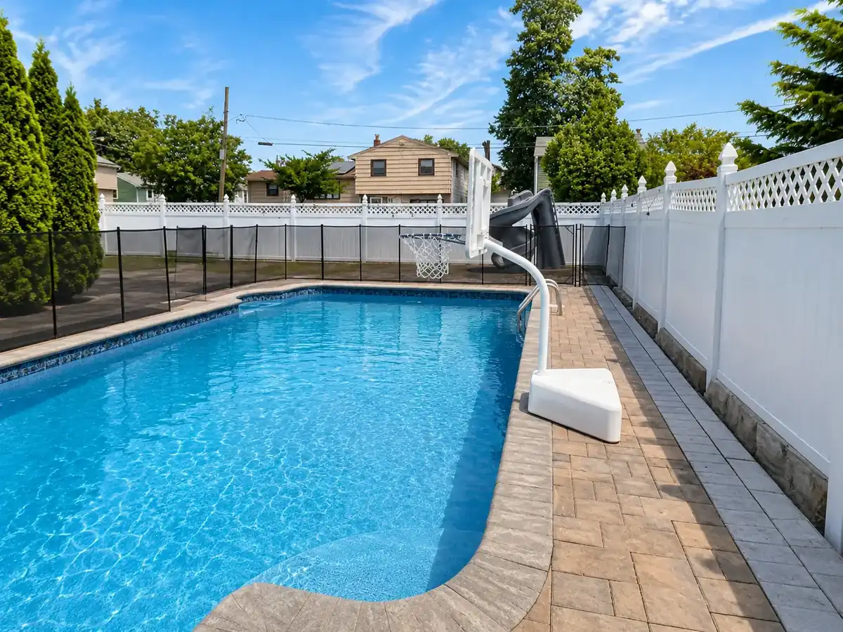 Black removable pool mesh safety fence around an inground pool